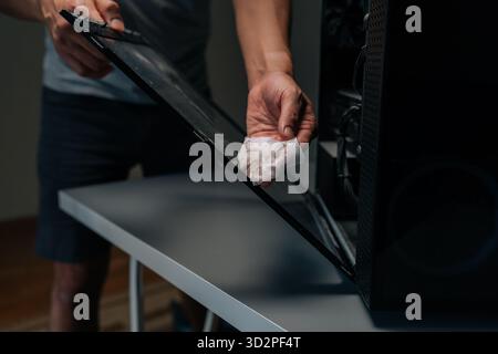 Photo recadrée d'un technicien en informatique essuyant le panneau vitré, éliminant l'accumulation de poussière et améliorant la circulation d'air interne pour un système électronique amélioré Banque D'Images