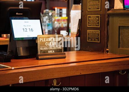 Gros plan d’une zone de bar avec un panneau indiquant « Veuillez garder dégagé – zone de collecte de verre ». Avis de santé et de sécurité dans un pub ou un restaurant. Banque D'Images
