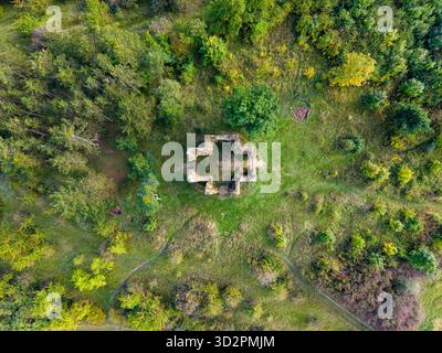 Vue aérienne des ruines de la chapelle de l'exaltation de la Sainte Croix à Bristev, entourée d'arbres verdoyants et d'un paysage naturel, mettant en valeur les vestiges de l'architecture historique. Banque D'Images