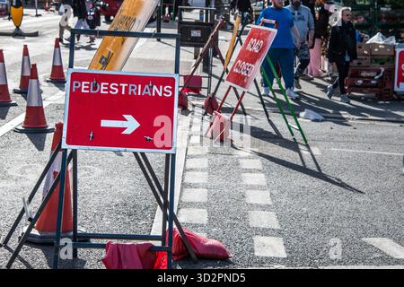 Panneau rouge « piétons » avec une flèche pointant vers la droite, indiquant le chemin correct pour les piétons le long d'une rue ou d'une passerelle du Royaume-Uni. Banque D'Images