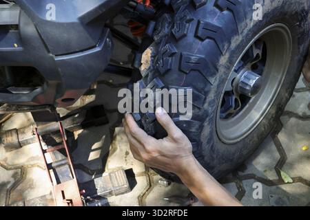 Main de mécanicien concentrée changeant de gros pneus tout terrain sur le véhicule. vue rapprochée du processus pratique de réparation, d'entretien et de service automobile sur li Banque D'Images