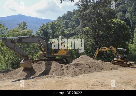 L'équipement lourd fonctionne sur le chantier de construction, déplaçant de gros tas de terre avec une pelle hydraulique. Des machines puissantes effectuent des travaux de terrassement contre-courant Banque D'Images