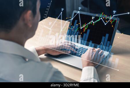 Un professionnel s'engage avec un ordinateur portable, analysant les graphiques numériques du marché boursier qui illustrent les tendances financières et les informations de données dans un w élégant Banque D'Images