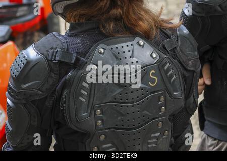 Vue arrière du cavalier en équipement de protection, femme en armure de sport et protecteur dorsal. Préparé pour une course de moto extrême, se sentant concentré avec elle en sécurité Banque D'Images