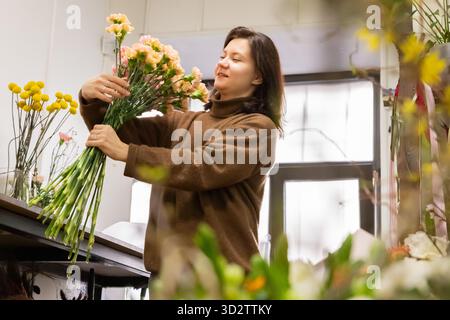femme fleuriste fait un bouquet dans son magasin de fleurs avec diverses fleurs Banque D'Images