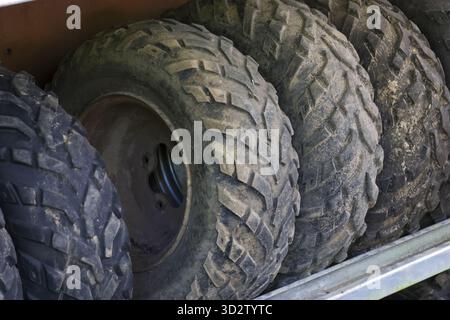 Gros plan sur la rangée de pneus et de roues tout-terrain sales et boueux avec bande de roulement robuste pour véhicule, suggérant l'aventure et le besoin de réparation ou de rempl automobile Banque D'Images