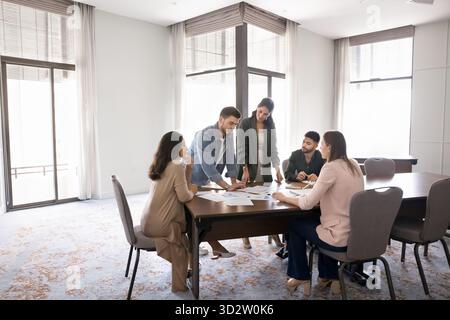 Équipe diversifiée examinant les graphiques imprimés pendant la séance de briefing ou de brainstorming Banque D'Images