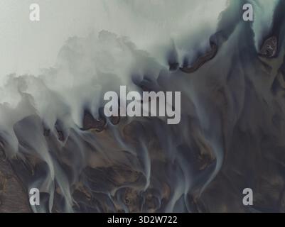 Vue aérienne des modèles de rivières glaciaires créant des motifs éthérés et fluides à travers le paysage, côte sud, Islande. Banque D'Images