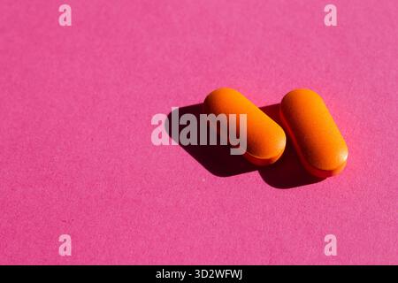 Deux pilules orange sur fond rose Banque D'Images