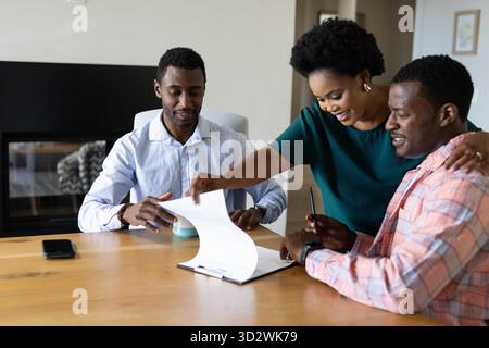 Examen de documents, amis afro-américains discutant ensemble et souriant à la maison. Collaboration, travail d'équipe, amitié, discussion, diversité, casual || autorisation du modèle Banque D'Images