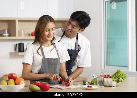 Un couple aime cuisiner ensemble, couper les légumes et partager un moment délicieux dans leur cuisine moderne Banque D'Images