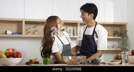 Un couple partage un moment tendre tout en cuisinant ensemble, mettant en valeur l'amour et la connexion dans la cuisine Banque D'Images