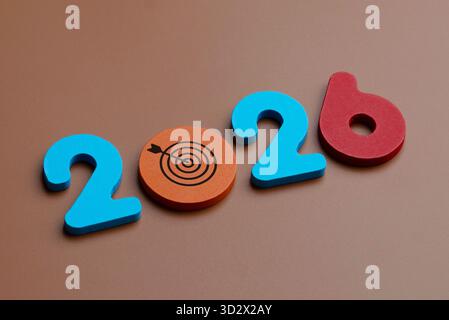 Numéros en bois colorés et un symbole de cible forment 2026. Objectifs futurs, stratégie commerciale, planification et établissement d'objectifs pour le concept de la nouvelle année. Banque D'Images