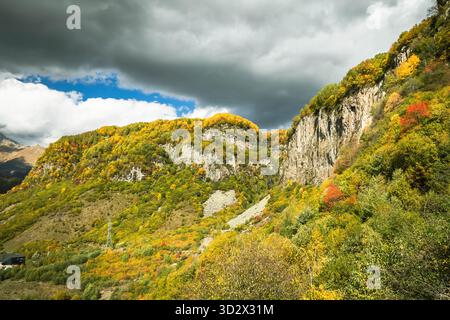 Paysage d'automne spectaculaire dans les montagnes du Caucase de Géorgie avec des falaises rocheuses et des couleurs de forêt vibrantes sous un ciel orageux. Terrain accidenté et sauvage Banque D'Images