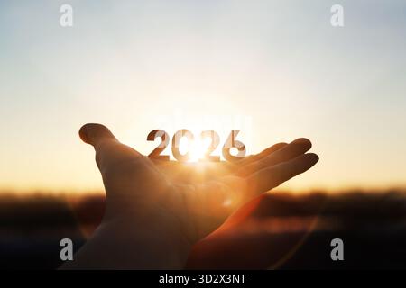 Lumière du soleil brillante brillante à travers les mains et le fond de lever du soleil pour le nouvel an 2026 Banque D'Images