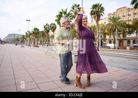 Couple senior dansant joyeusement sur la promenade de la ville Banque D'Images