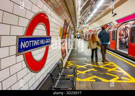 En regardant le quai à la station de métro Notting Hill Gate London, quelques passagers passent devant un train qui est garé sur le quai. Banque D'Images