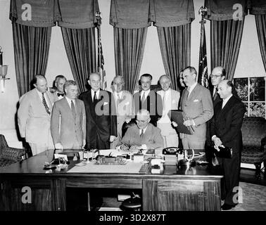 WASHINGTON DC, États-Unis - 24 août 1949 - le président américain Harry Truman signe le document de mise en œuvre du Traité de l'Atlantique Nord à son bureau du Bureau ovale de la Maison Blanche à Washington DC, aux États-Unis, sous le regard de plusieurs dignitaires. De gauche à droite : Sir Frederick Hoyer Millar, chargé d'affaires, Royaume-Uni ; l'Ambassadeur Henrik de Kauffmann, du Danemark ; W d Matthews, chargé d'affaires, Canada ; le Secrétaire à la Défense Louis A Johnson ; l'Ambassadeur Wilhelm Munthe de Morgenstierne, de Norvège ; l'Ambassadeur Henri Bonnet, de France ; le Baron Robert Silvercruys, Ambassadeur de Belgique ; l'Ambassadeur Pedro Teotóni Banque D'Images