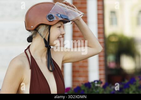 Jeune femme cavalier dans le casque et scooter de moto dans la rue de la ville Banque D'Images