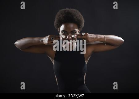 La jeune femme noire afro-américaine qui applique avec les doigts de la crème blanche se salir sur son visage avec l'émotion joueur américain de football Banque D'Images