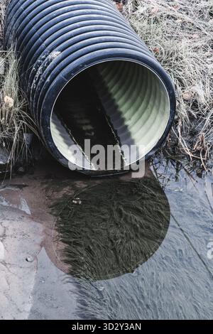 Un tuyau en plastique noir pour les déchets industriels a été apporté à la rive. Écologie et pollution Banque D'Images