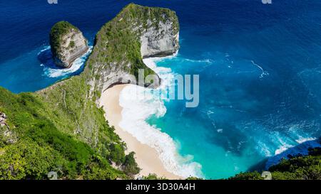 Plage de sable blanc isolée nichée sous une falaise verdoyante spectaculaire par une journée ensoleillée à Bali. Banque D'Images