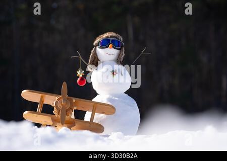 Bonhomme de neige avec décorations festives. Bonhomme de neige dans la cour hivernale. Bonhomme de neige drôle avec une expression joyeuse à l'extérieur. Bonhomme de neige avec écharpe et chapeau pour l'hiver Banque D'Images