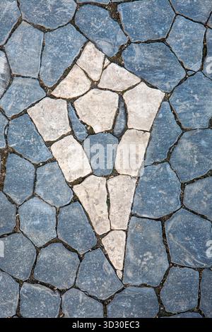 Motif abstrait dans le trottoir traditionnel portugais calçada, fabriqué à partir de pierres calcaires bleues et blanches à Lisbonne. Banque D'Images