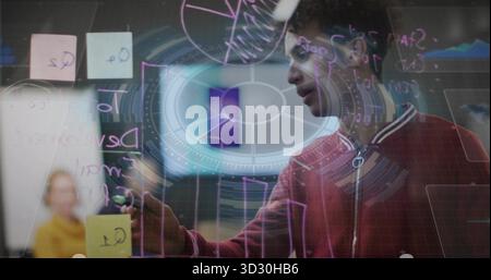 Annoter l'homme dans le pull rouge en utilisant le marqueur sur la cloison dans la salle de conférence avec des notes collantes pastel Banque D'Images