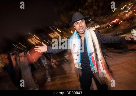 À Los Angeles, un fan encourage les Dodgers. La police attend à l'extérieur d'un bar pour disperser la foule tandis que les fans à l'intérieur encouragent l'équipe à travers des manches supplémentaires. 1er novembre 2025. Banque D'Images