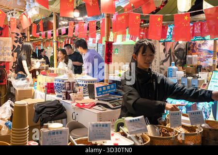 Dali, Chine - 10 octobre 2025 : vue nocturne animée de la rue animée des habitants vendant de la nourriture et des boissons avec des touristes dans la ville antique de Dali, Yunnan, Chine. Banque D'Images