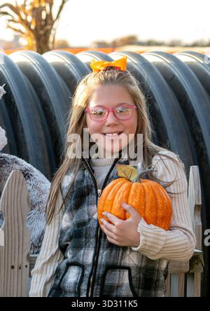 Fille souriante tient une petite citrouille pour Halloween Banque D'Images