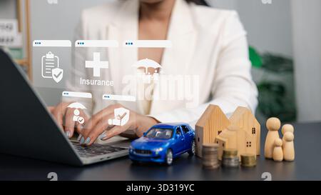Femme d'affaires travaillant sur ordinateur portable avec icône d'assurance numérique, concept de protection familiale, de santé, de voiture et de sécurité financière à domicile en utilisant la techn moderne Banque D'Images