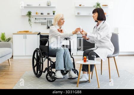 Médecin donnant des médicaments à une femme âgée en fauteuil roulant Banque D'Images