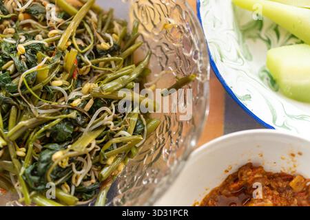 Gros plan sur la cuisine traditionnelle indonésienne. Un bol de salade de légumes avec épinards d'eau, germes de haricots et sauce Chili. Banque D'Images