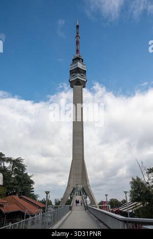 Regardant la Tour Avala à Belgrade avec son design brutaliste. Les gens marchant vers l'entrée donnent une impression d'échelle. Octobre 2025. Banque D'Images