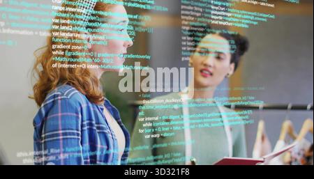 Deux collègues discutent des extraits de code au bureau avec classeur, usine, porte-vêtements Banque D'Images