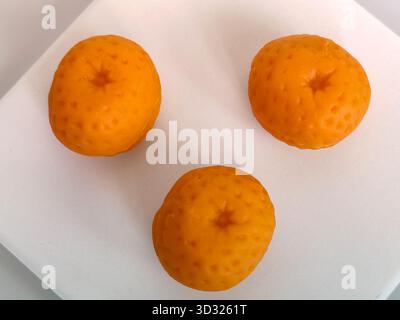 Les bonbons au massepain en forme d'orange sont soigneusement disposés sur fond blanc. Copier l'espace. Mise au point sélective. Banque D'Images