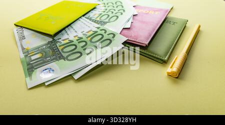 Cent billets en euros avec passeports colorés et stylo jaune sur table Banque D'Images