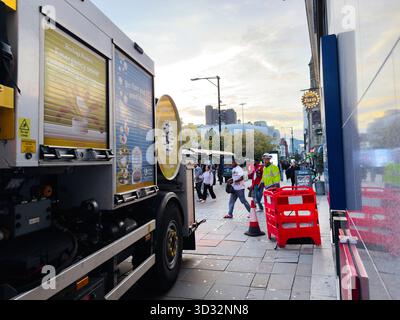 Manchester, Royaume-Uni - 29 septembre 2025 : scène de rue urbaine dynamique à Manchester avec un food truck, des piétons et des barrières lors d'une journée animée. Banque D'Images