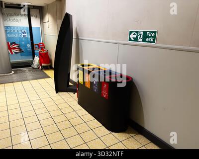 Manchester, Royaume-Uni - 29 septembre 2025 : la zone intérieure de Manchester comprend un panneau de sortie de secours, des poubelles et un chariot. Banque D'Images