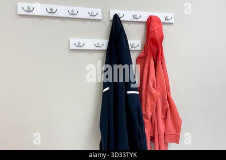 Vestes d'extérieur d'automne et manteaux suspendus sur des cintres dans une armoire en bois dans le couloir Banque D'Images