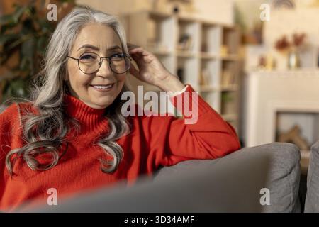 Femme souriante. Femme aux cheveux longs en rouge à la maison et se sentant positive Banque D'Images