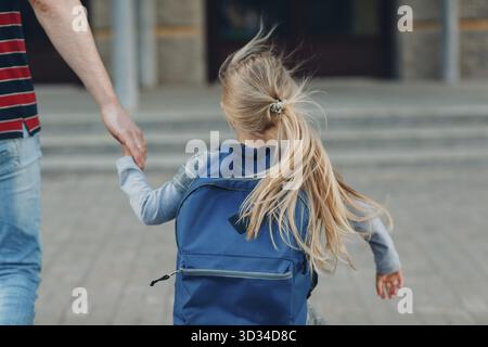 Vue arrière du père de retour à l'école avec son sac à dos pour fille Banque D'Images