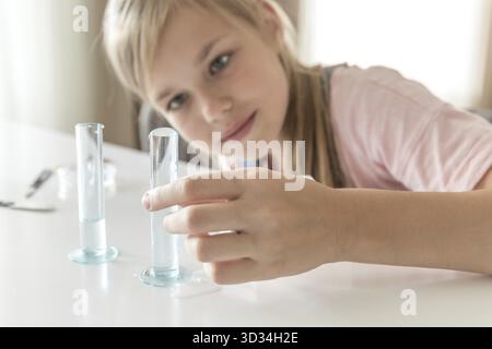 Fille faisant l'expérience chimique et étudiant les ingrédients pour l'essai avec tube Banque D'Images
