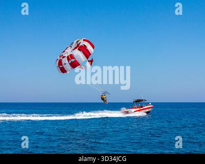Touristes parachute ascensionnel ou parachute ascensionnel à partir d'un bateau à moteur dans la mer Méditerranée au large de la côte de Protaras dans l'est de Chypre. Banque D'Images