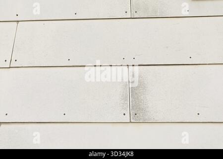 Quelques carreaux asbest blancs vieux et usés sur un mur extérieur de la maison. Les carreaux de mur Asbest étaient populaires dans les jours anciens. Beaucoup de maisons ont encore ces trois de santé Banque D'Images
