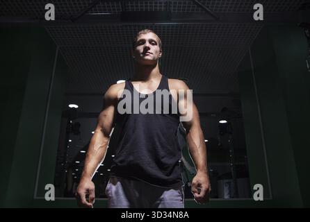 Portrait de jeune sportif musclé regardant la caméra dans gym.From Below Banque D'Images