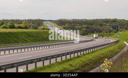 Une autoroute sinueuse traverse un paysage luxuriant, avec des arbres et de la verdure encadrant la route par une journée lumineuse Banque D'Images