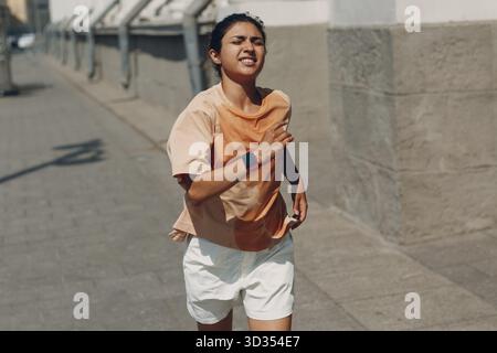Jeune femme indienne jogging dans un t-shirt sueur humide dans la rue de la ville Banque D'Images